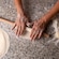 Two hands kneading dough on a floured surface